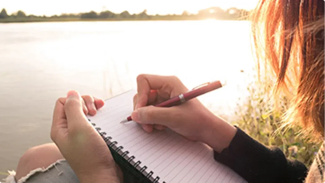 水辺でノートに字を描いている