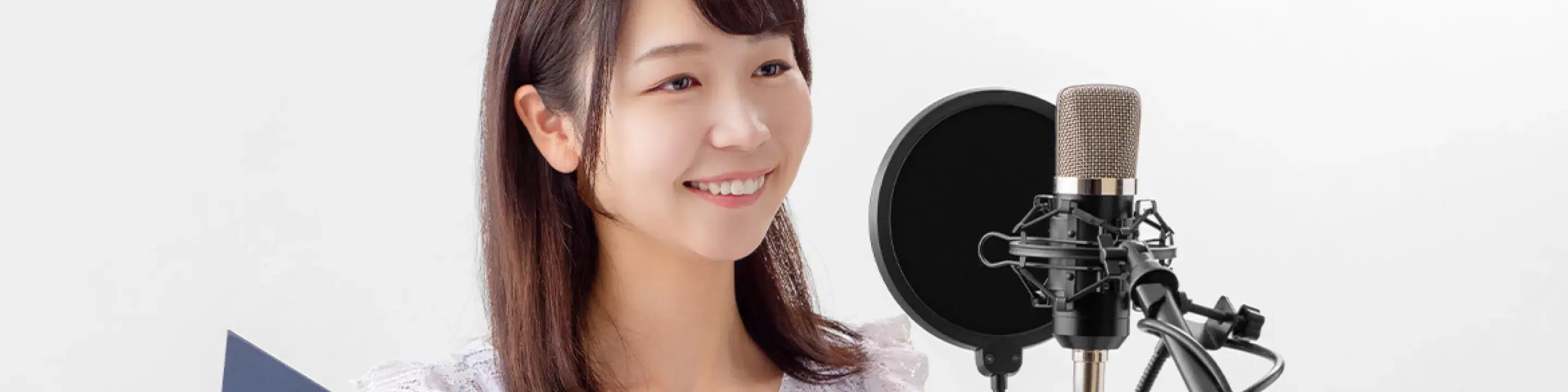 マイクに向かって女性がレコーディングしているイメージ
